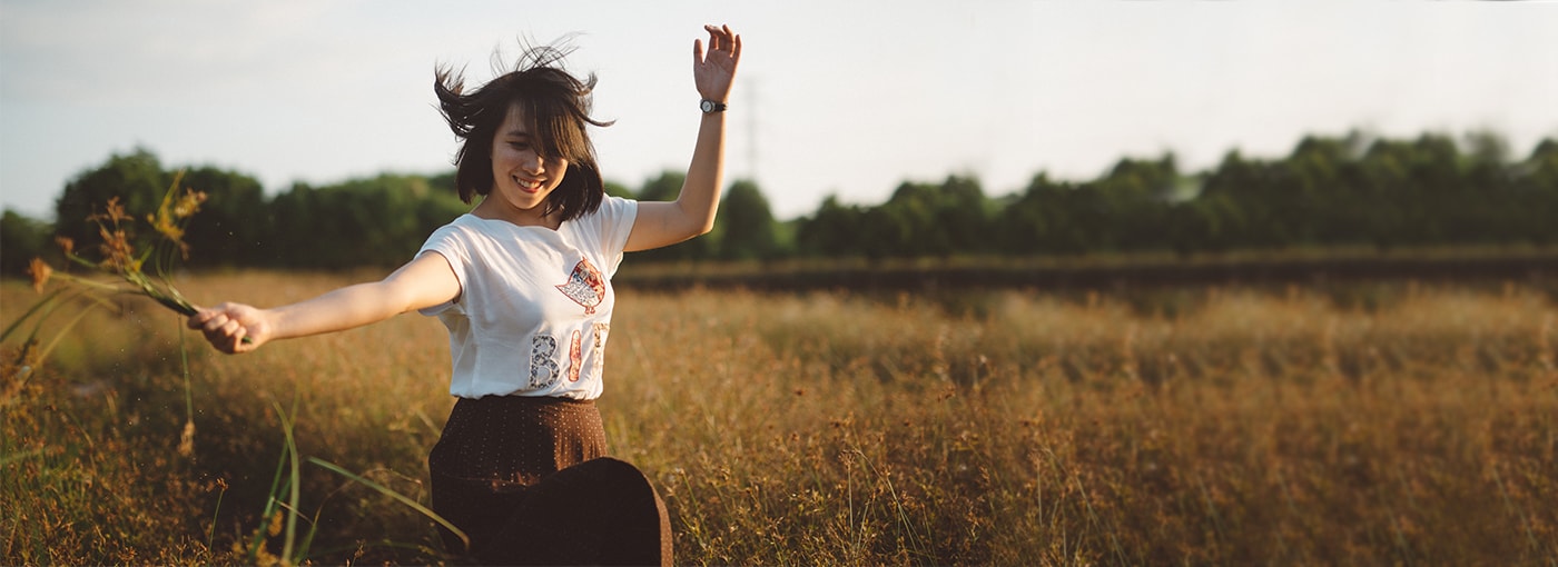 Young carefree woman frolicking in open field.