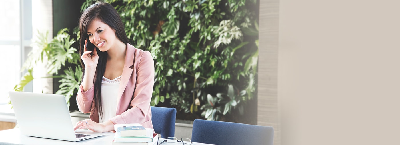 Young professional woman working on phone & laptop.